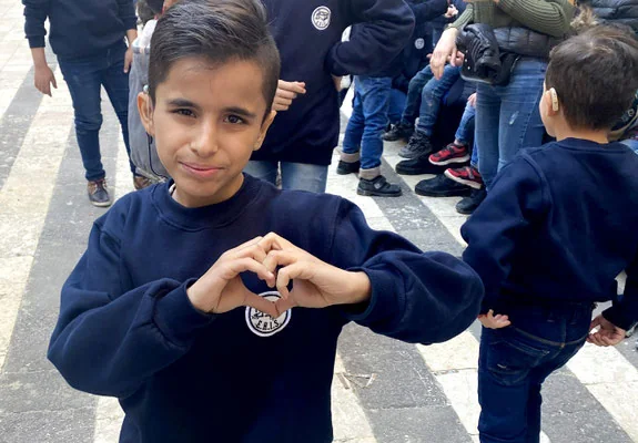 A boy makes a heart during an activity