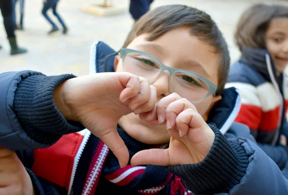 A child with glasses makes a heart