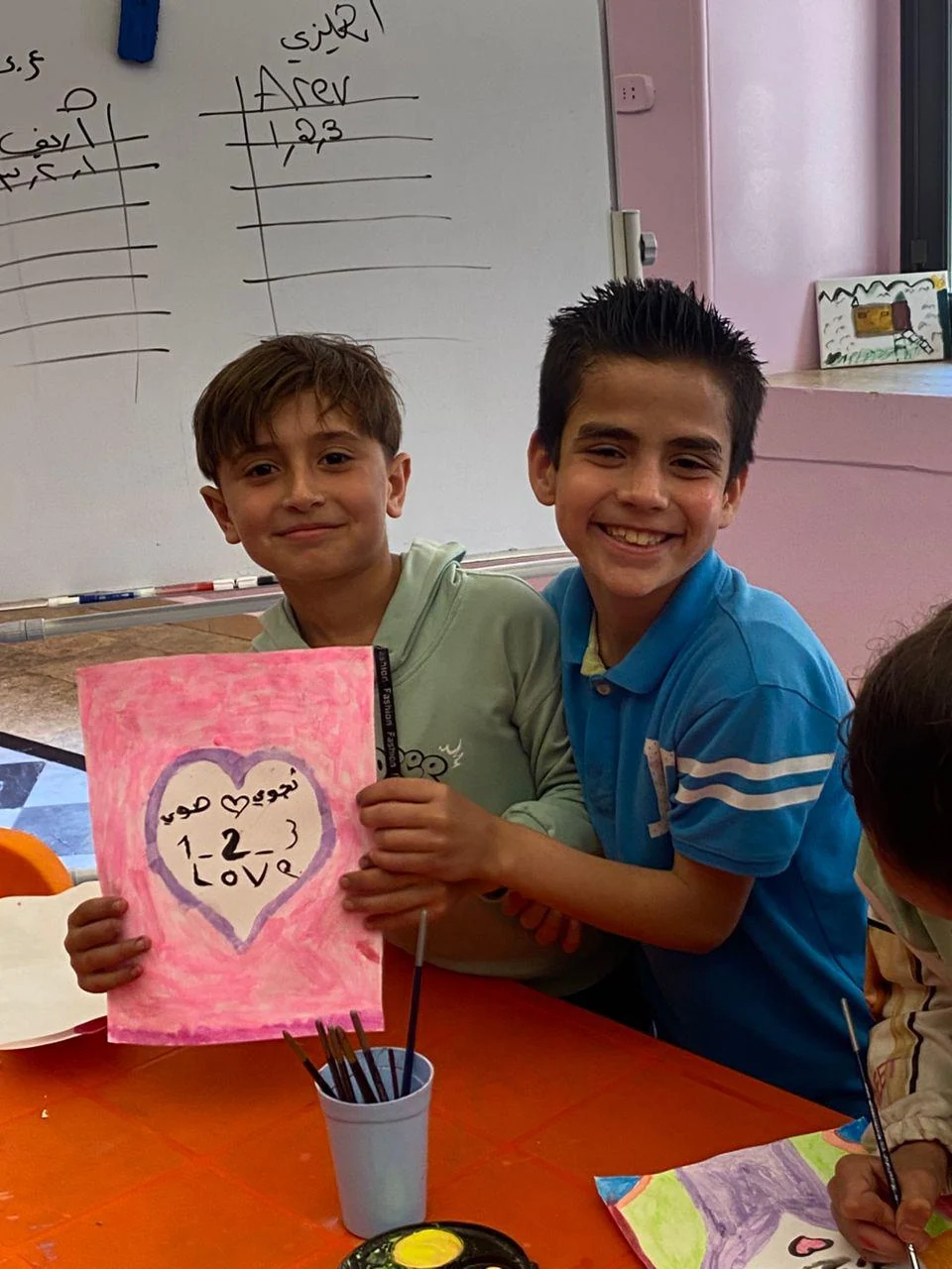 طفلان يعرضان رسماً فيه كلمة love.