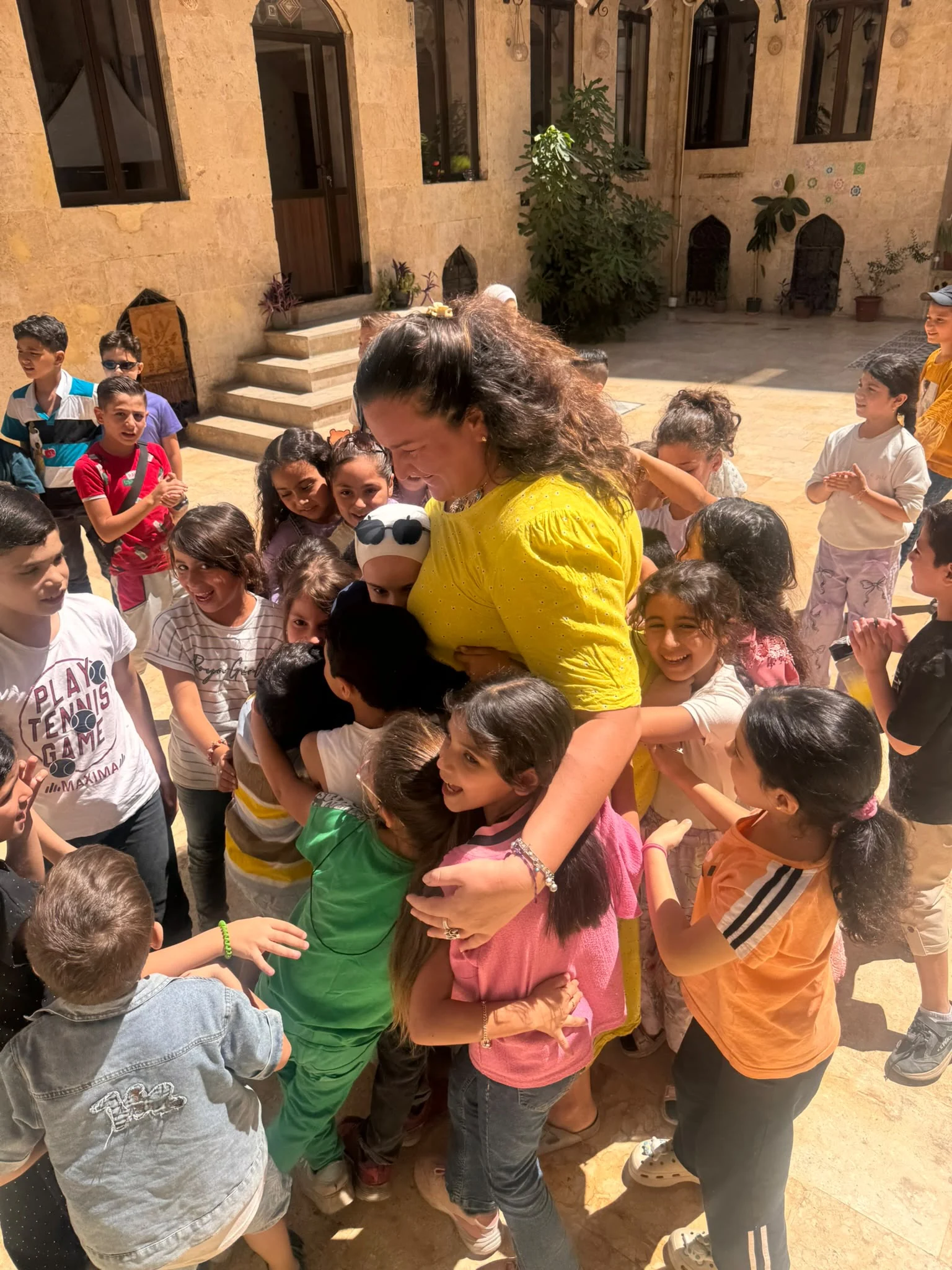 Soumaya Hallak surrounded by children in the courtyard of the 123 HOPE centre in Aleppo.